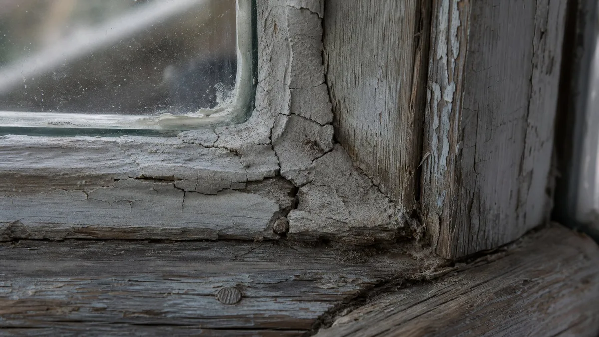 Altes, rissiges Fensterkitt an einem Holzfensterrahmen in einem Schweizer Altbau