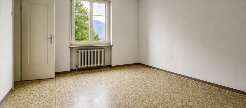 Leeres Zimmer einer älteren Schweizer Mietwohnung mit gemustertem Novilon-Bodenbelag