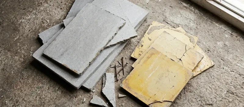 Zerbrochene Asbestzementplatten-Fragmente auf einem Boden